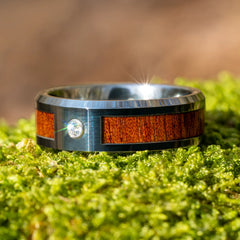 Adamantius tungsten ring with koa wood inlay on grass by Natural Rings